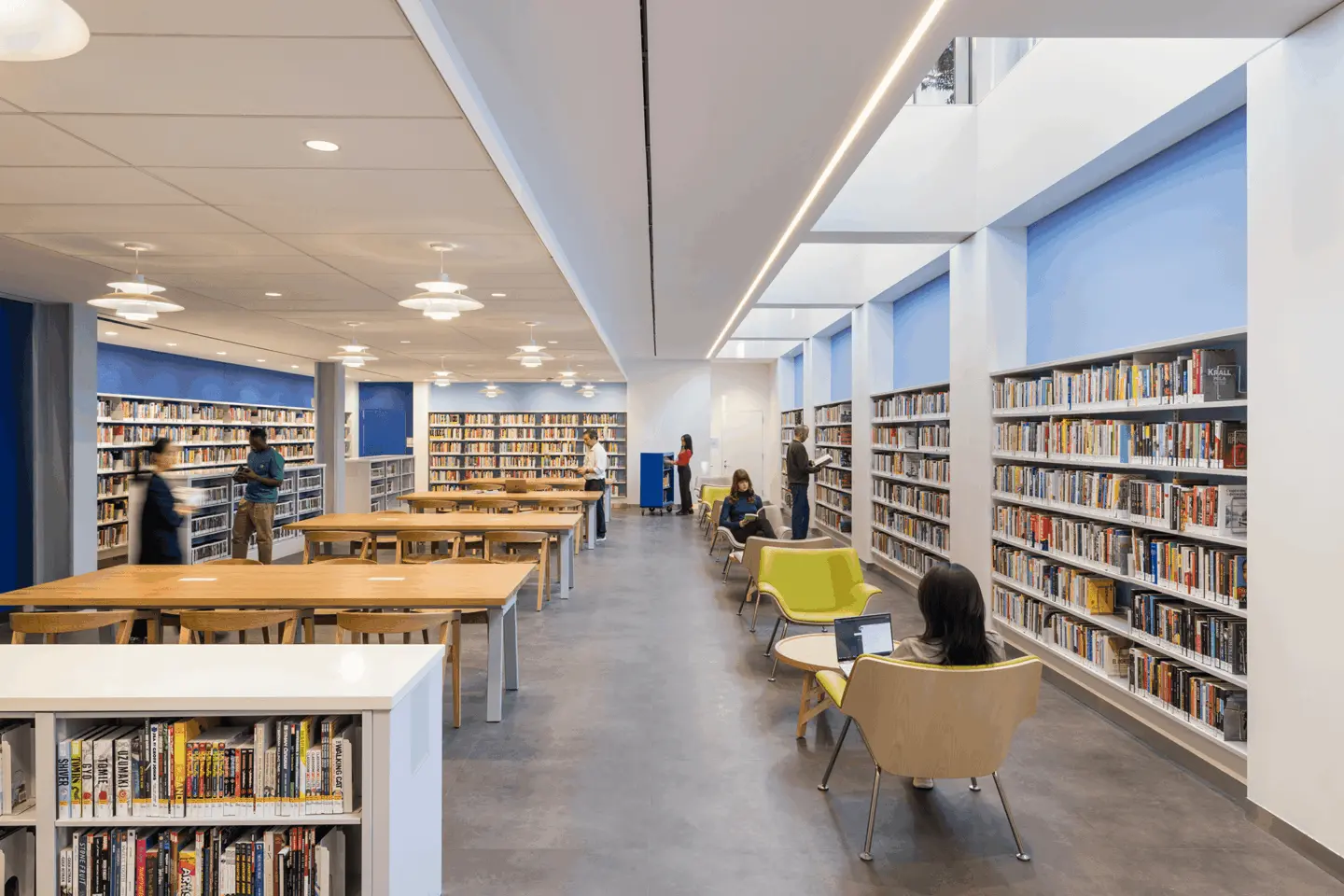 Multiple people standing and sitting in the Brooklyn public library