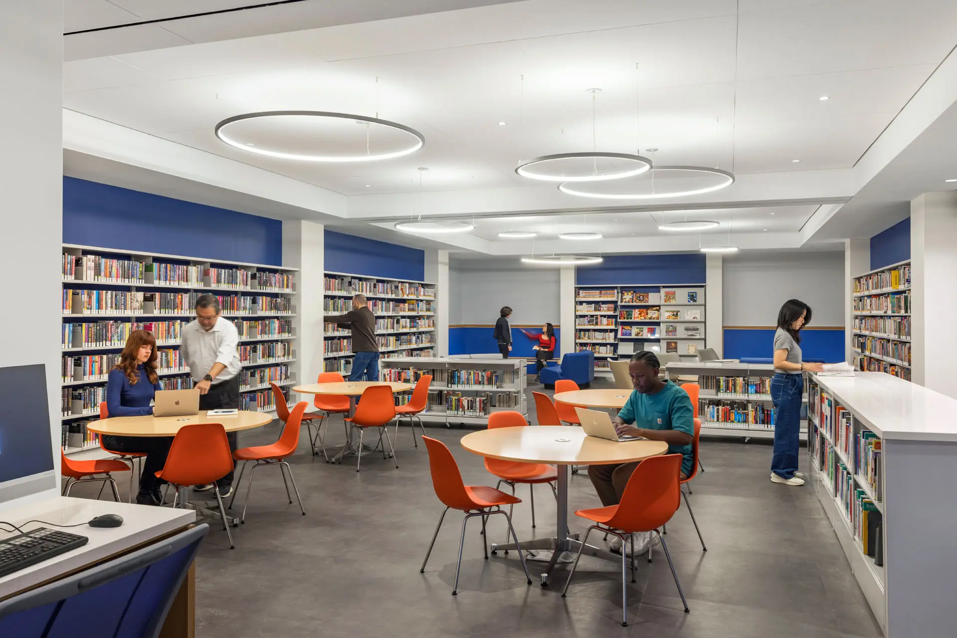 Rendering of Bookshelves lining walls with center tables and people with laptops at tables