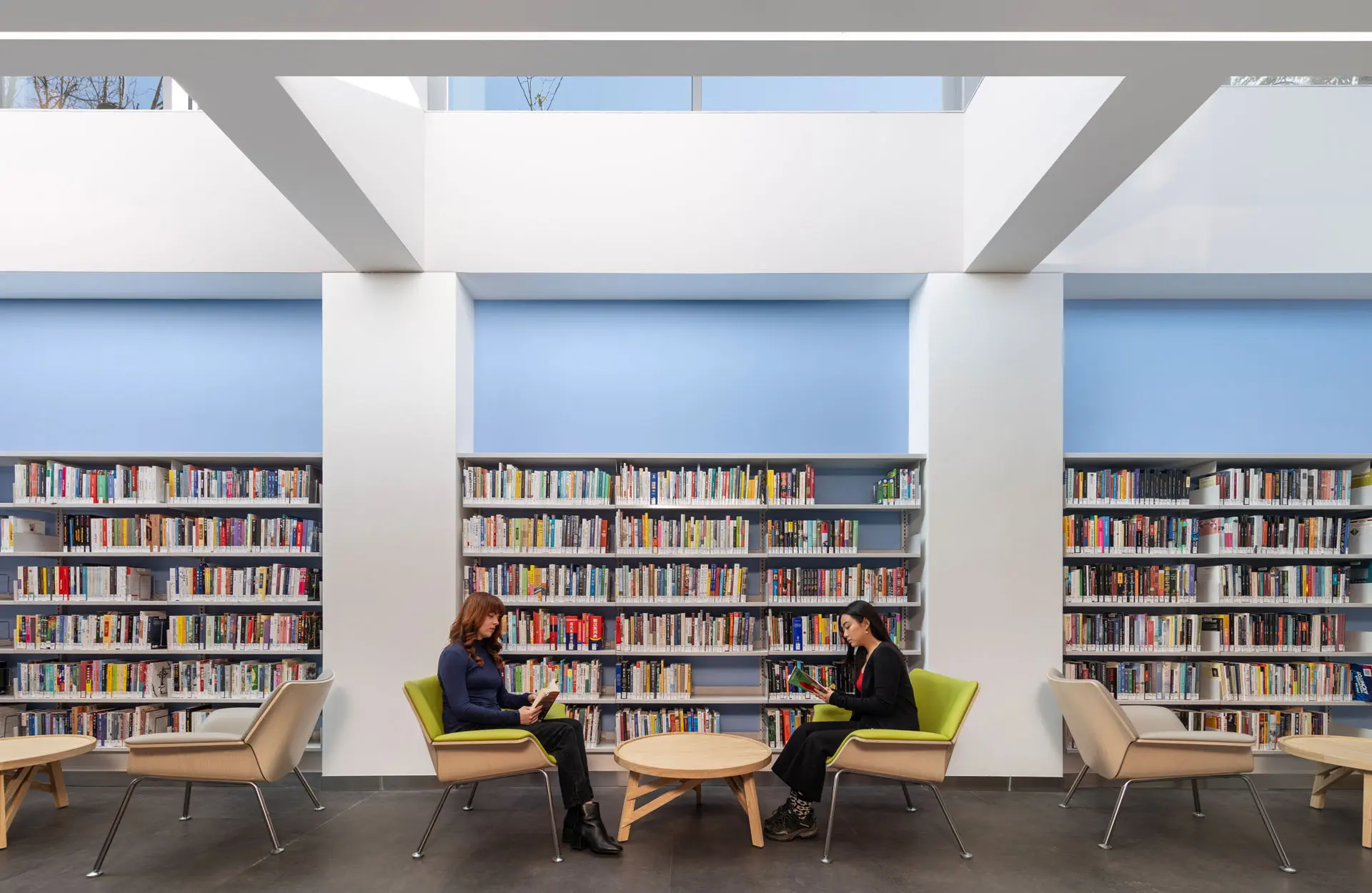 Rendering of Two women sitting with books at library in front of wall of books