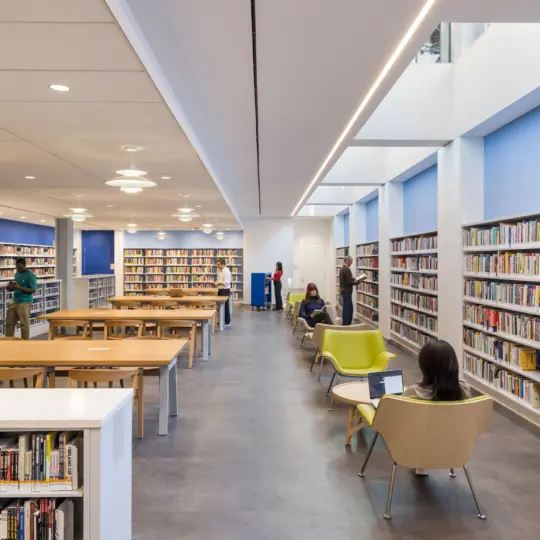 Rendering of Library patrons sitting and walking around library area with walls of books and center tables