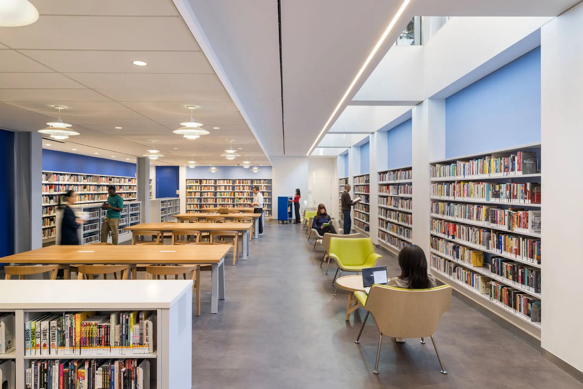 Rendering of Library patrons sitting and walking around library area with walls of books and center tables