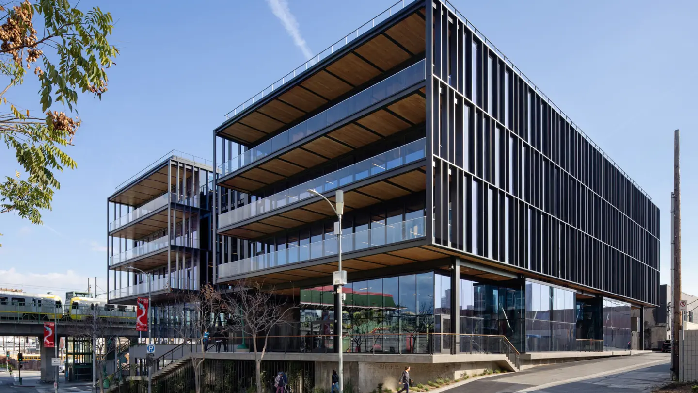 Corner picture of the five story steel, glass, and wooden 843 North Spring Street building in front of a train