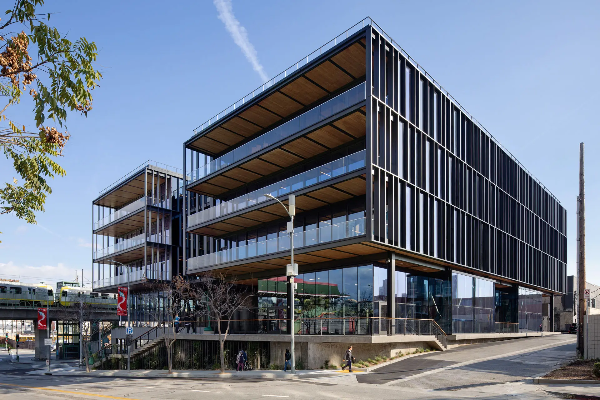 Corner picture of the five story steel, glass, and wooden 843 North Spring Street building in front of a train