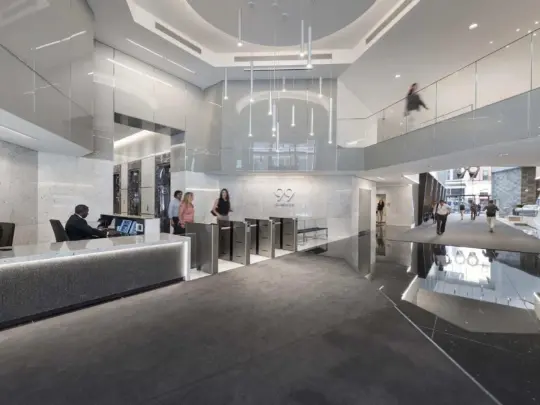 Interior image of people walking through hallway with white marble and pendant lighting