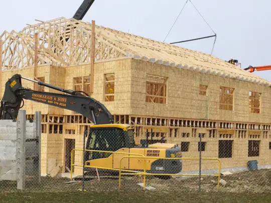 Wooden framing and a backhoe of the Pomfret Academy