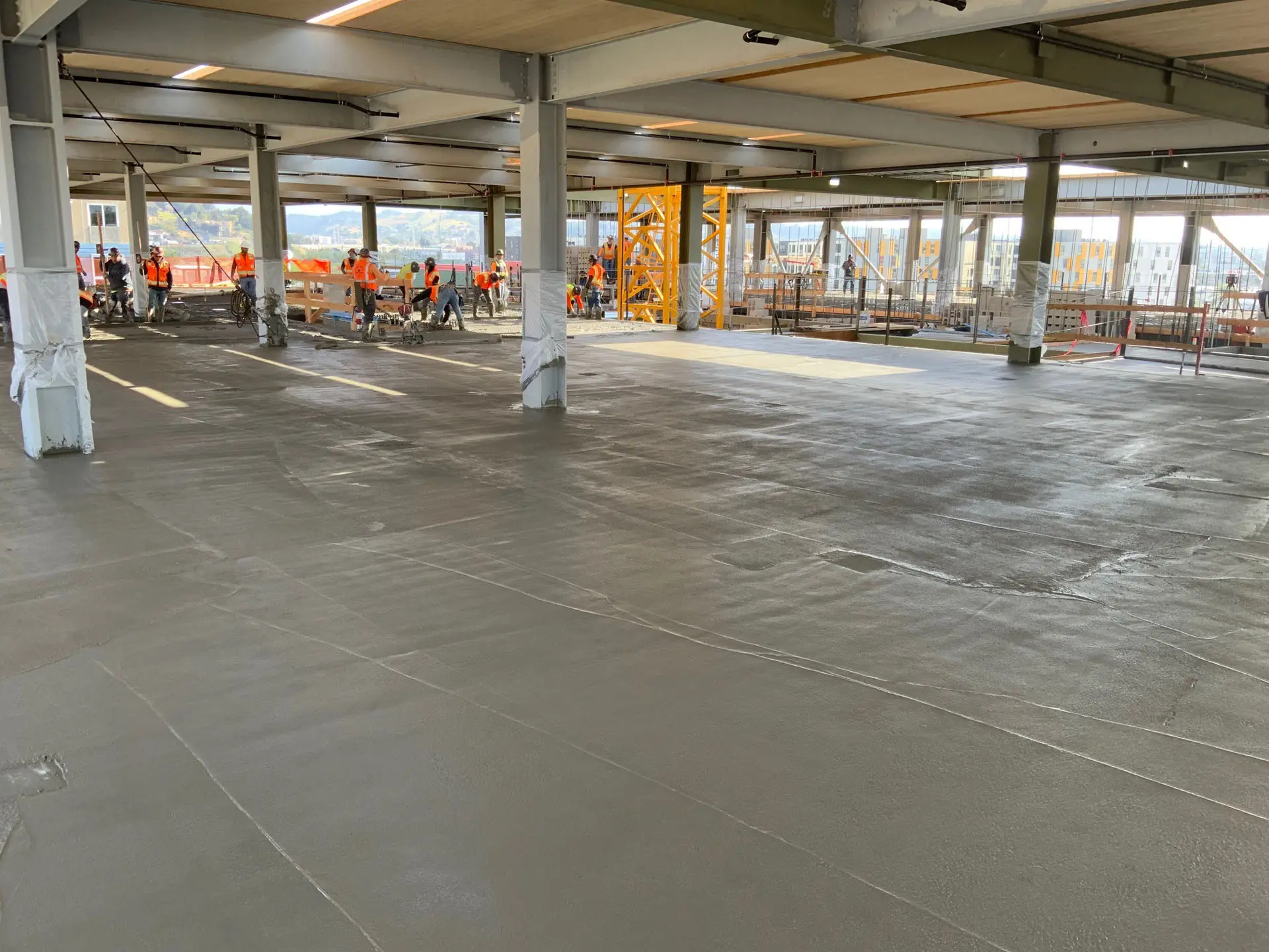 Concrete floors being finished by workers in safety vests at the 843 North Spring Street building