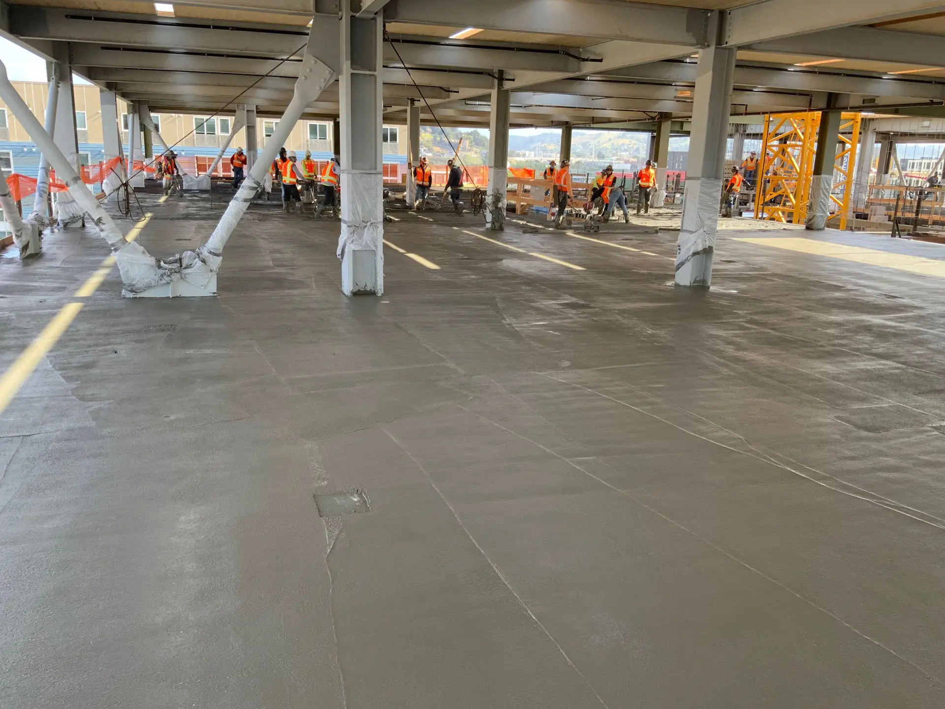 Concrete floors being finished by workers in safety vests at the 843 North Spring Street building
