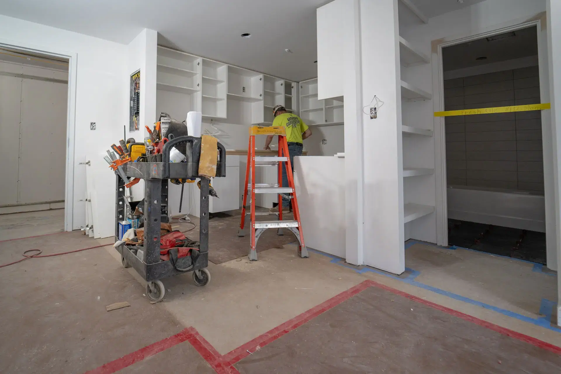 Worker installing millwork in kitchen of apartment in Harvard Soldiers Field Apartments