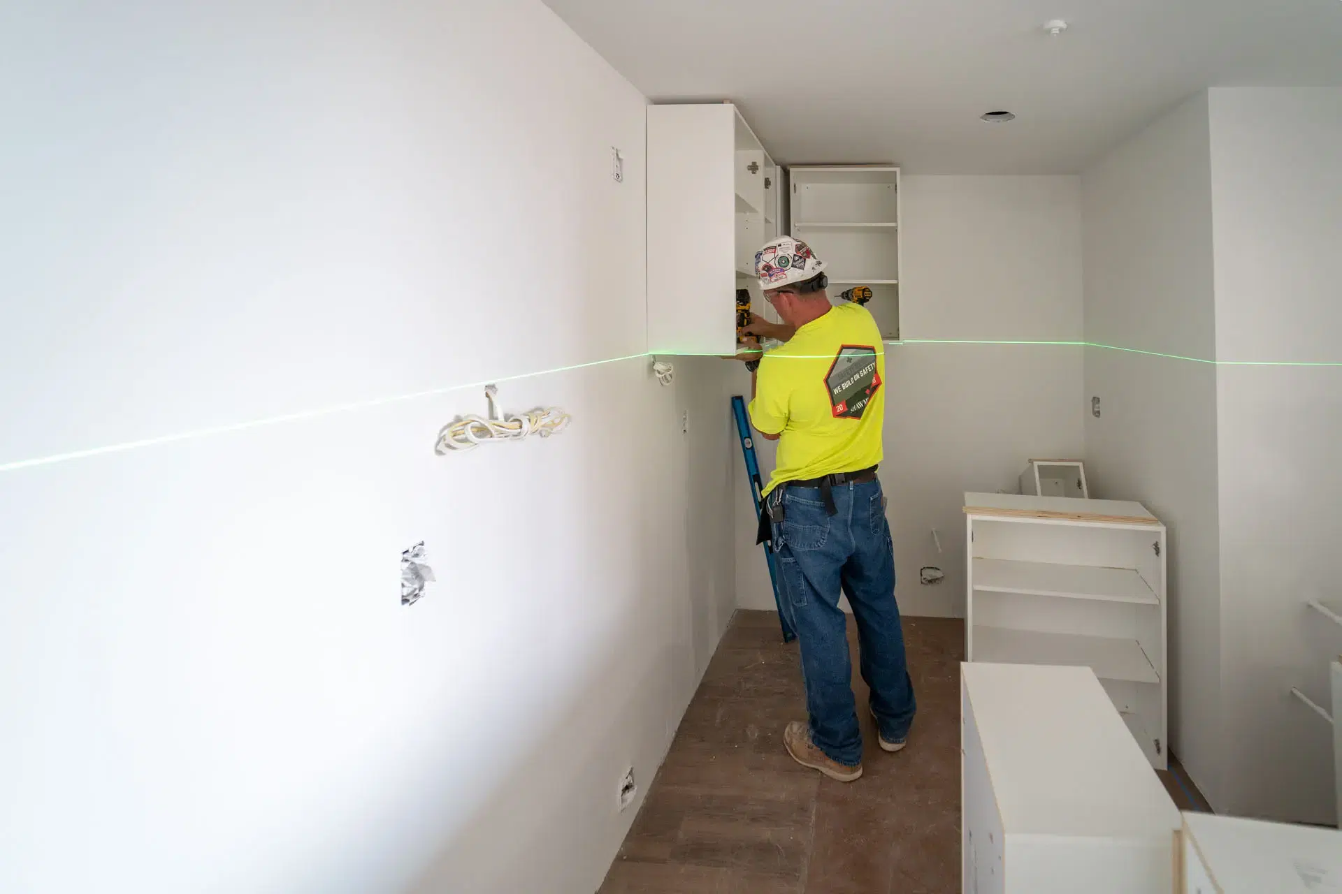 Worker installing millwork in kitchen of apartment in Harvard Soldiers Field Apartments