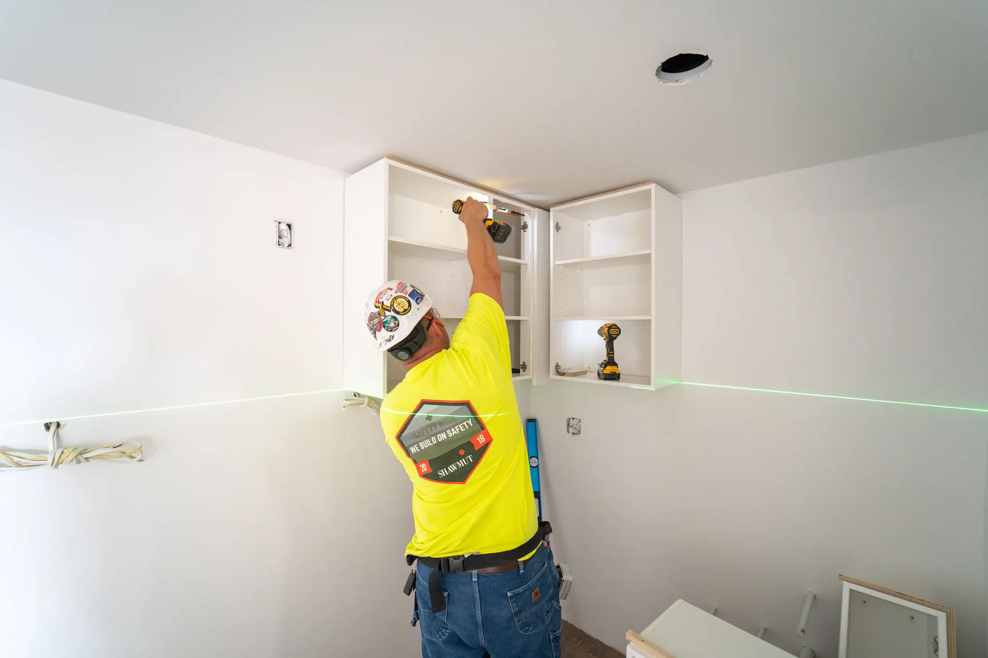 Worker installing millwork using a laser in kitchen of apartment in Harvard Soldiers Field Apartments