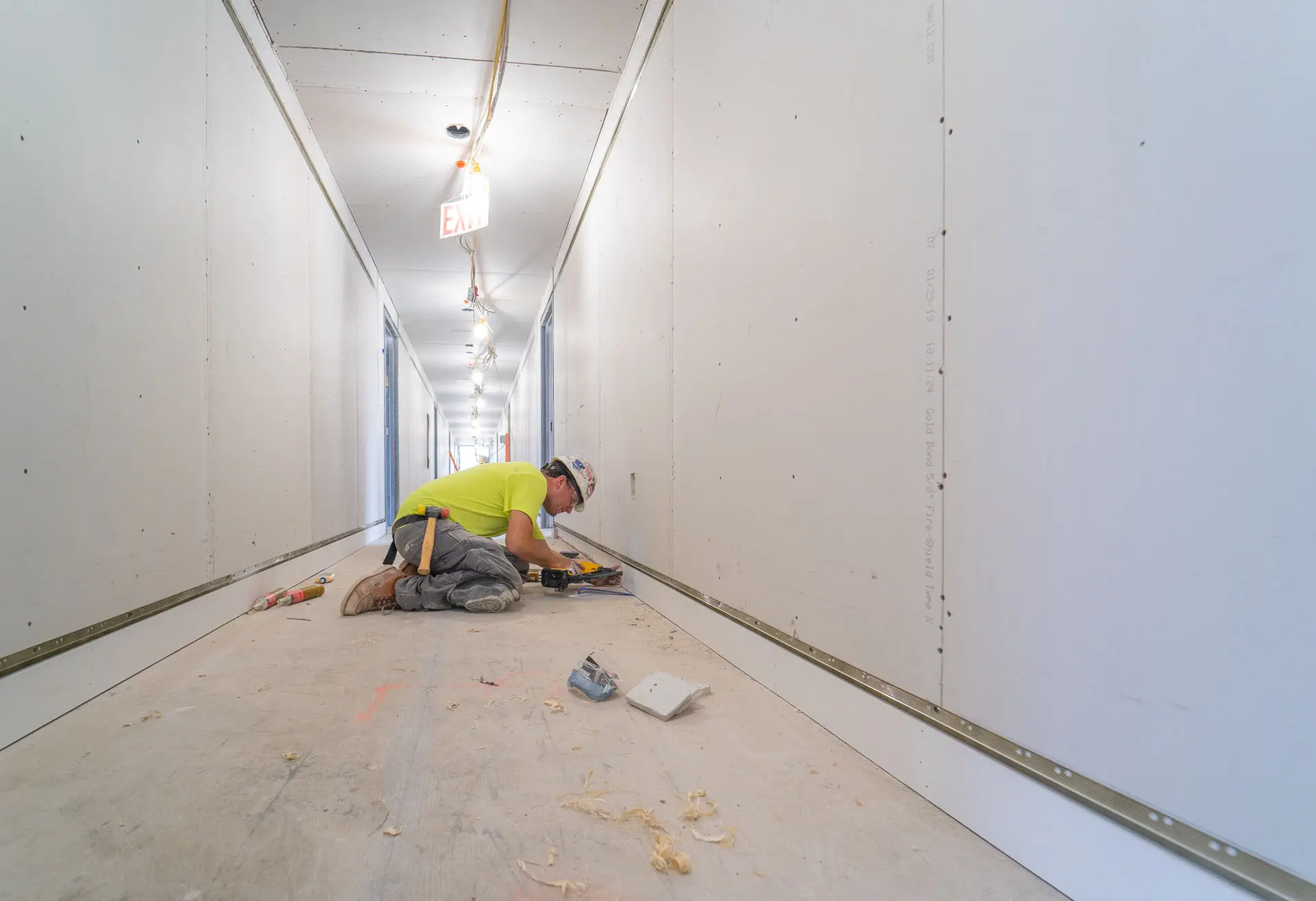 Worker in safety gear on floor installing baseboard