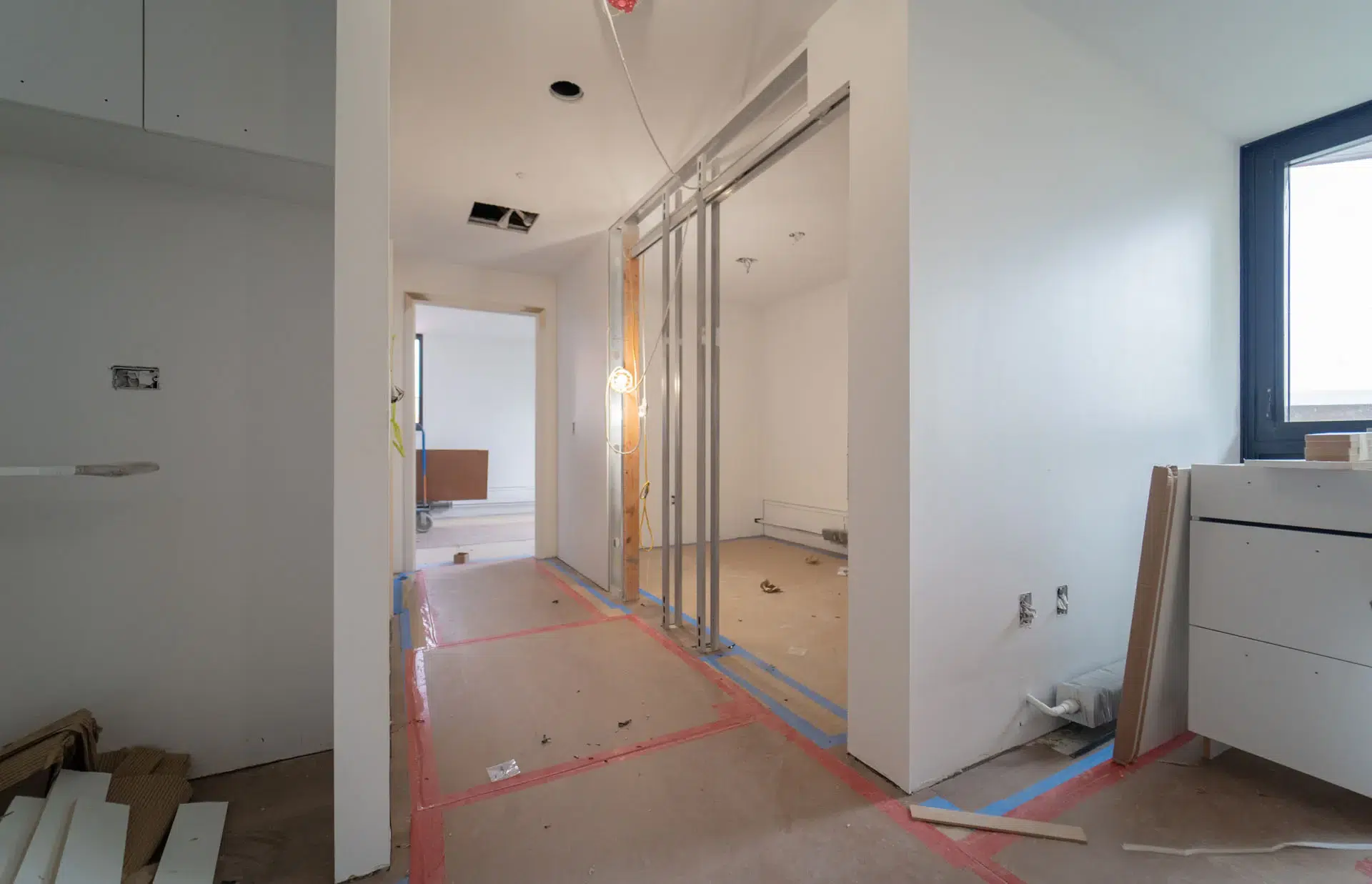 Interior of hallway under construction with view into four areas with construction materials