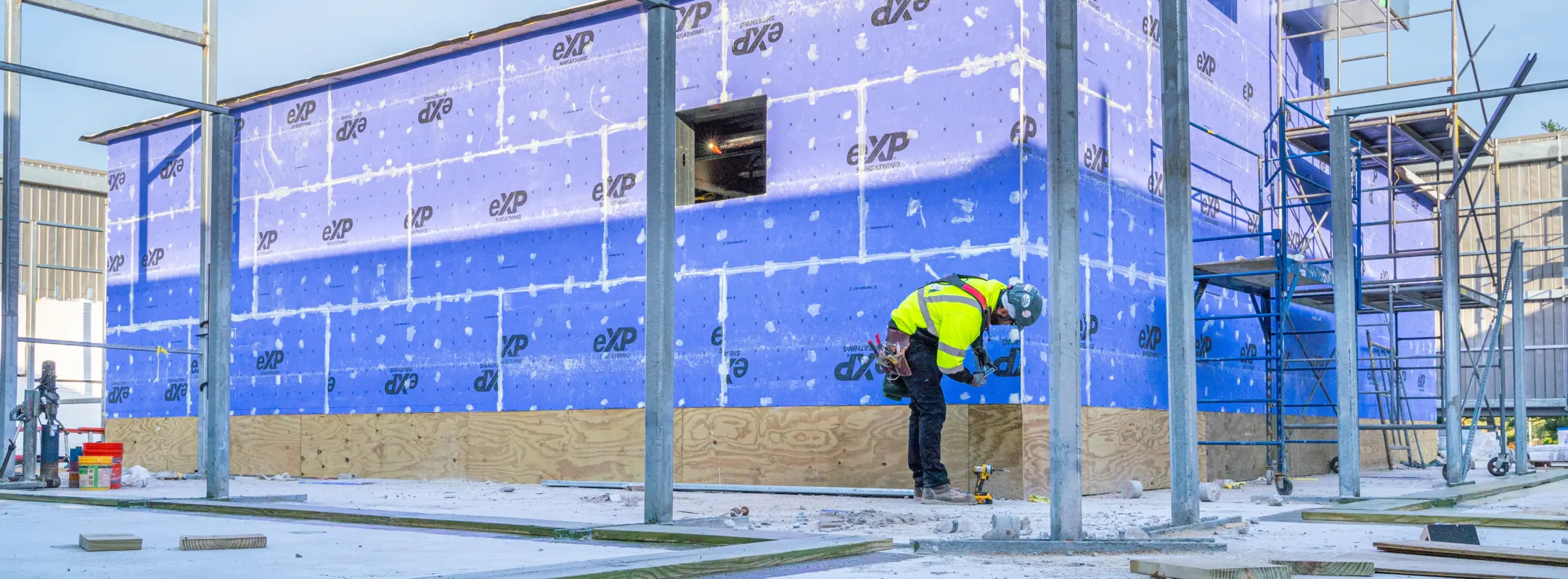 Person working on gypsum sheathing on building exterior
