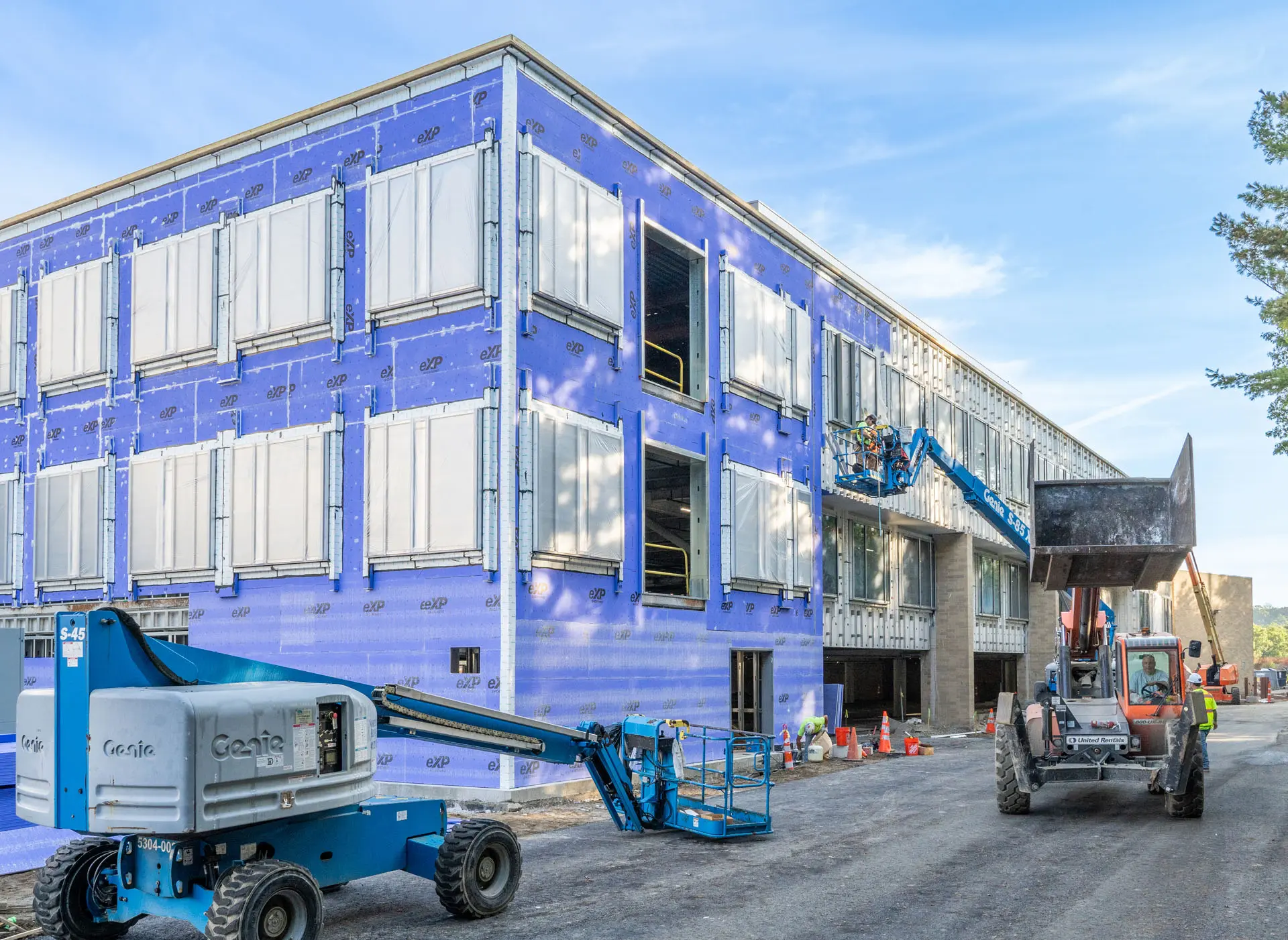 Worker on cherrypicker at second level of Riverside Labs building under construction