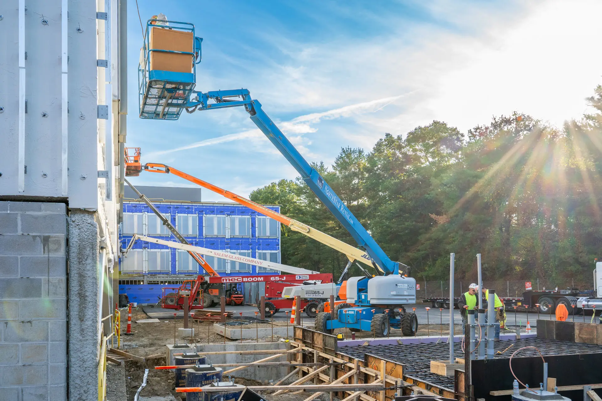 Four cherrypickers working at different levels of the Riverside Labs building under construction