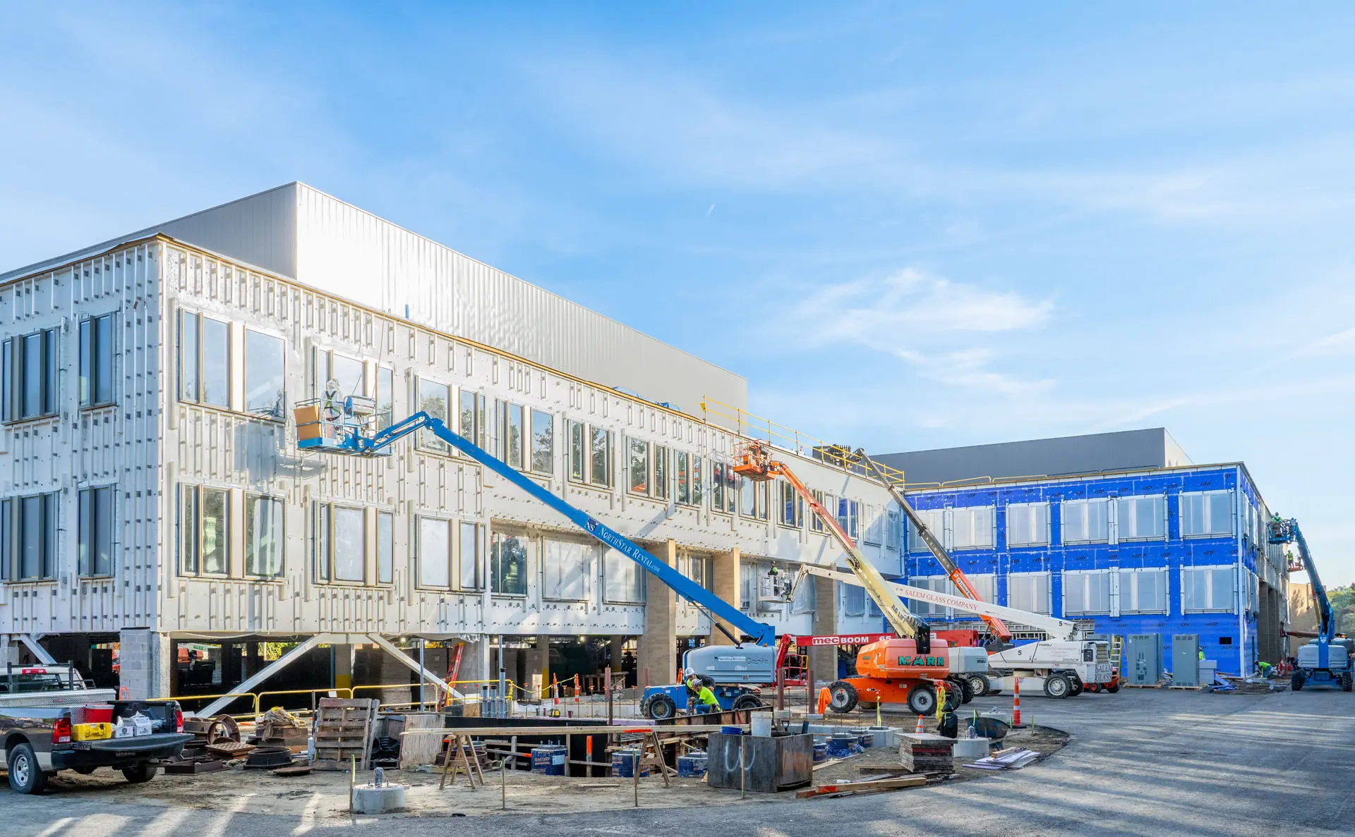 Three cherrypickers working at different levels of the Riverside Labs building under construction