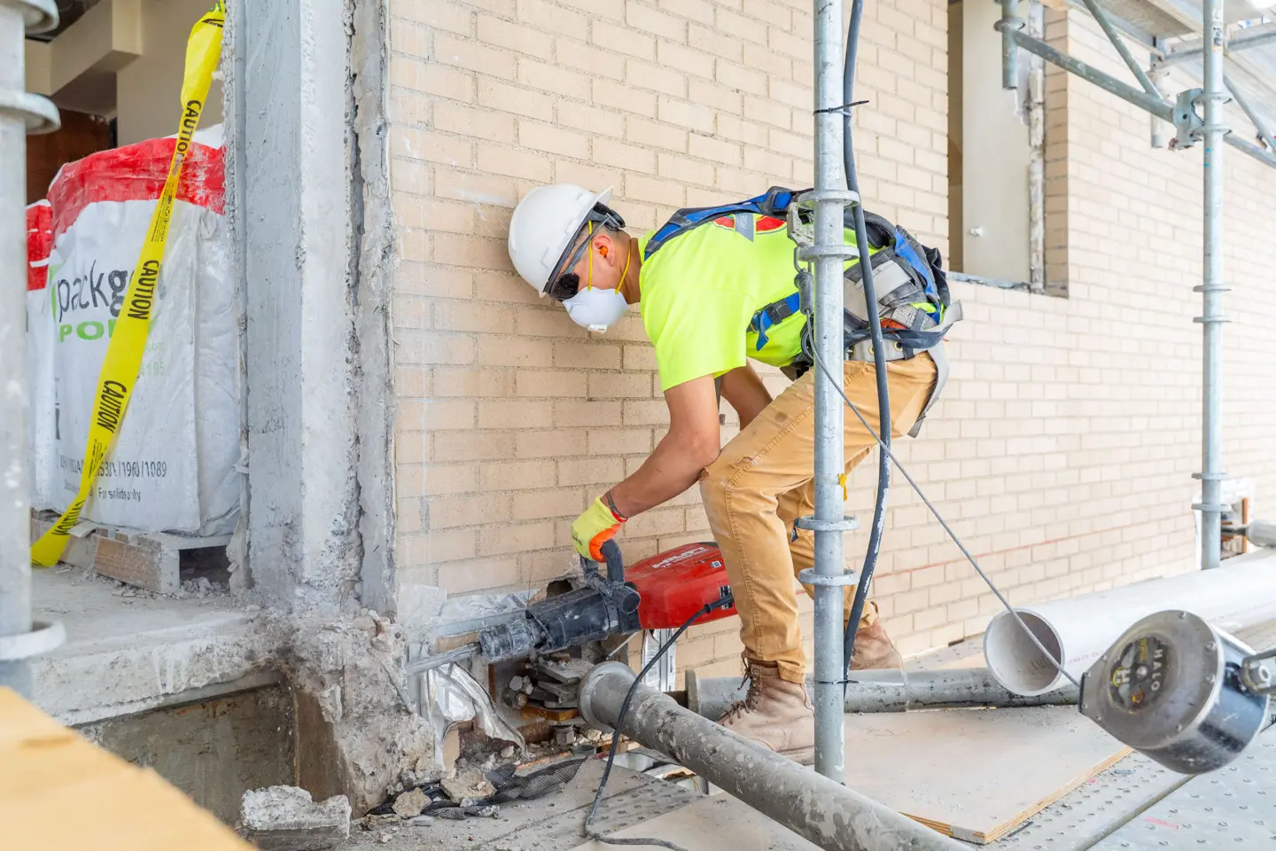 Man demolishing wall with handheld jackhammer
