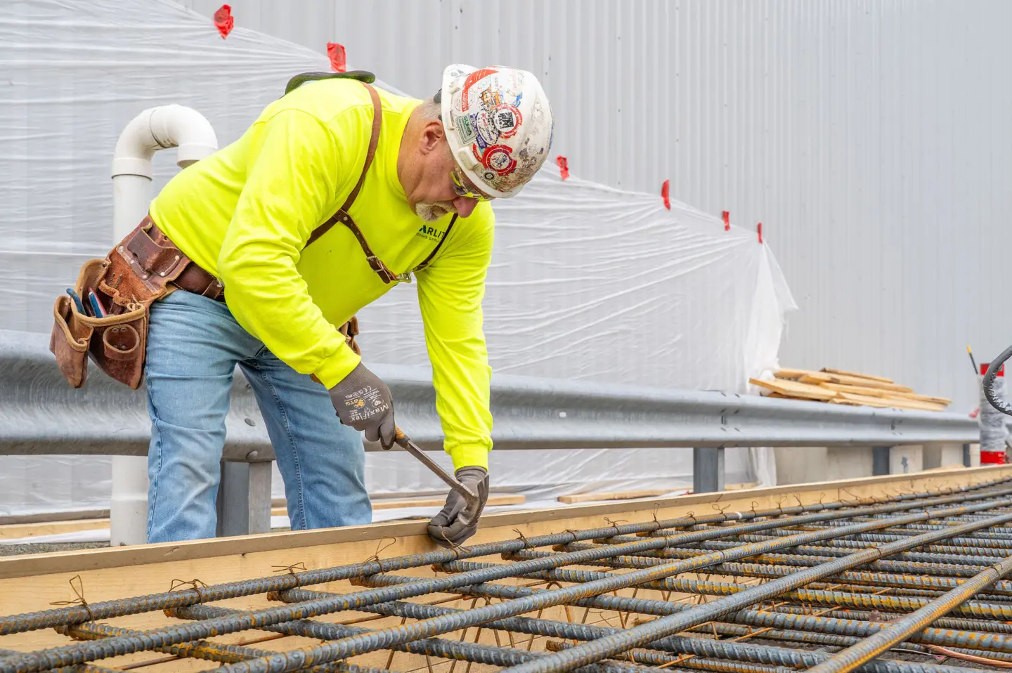Person securing metal rebar during concrete construction