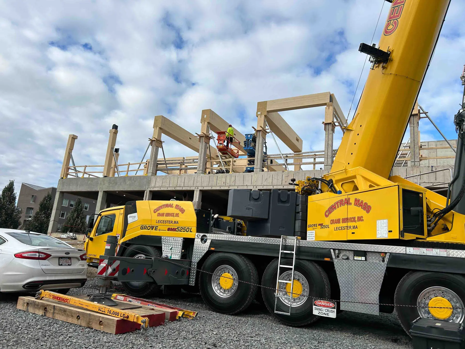 Yellow crane and man on scissor lift in cross timber building at Amherst College