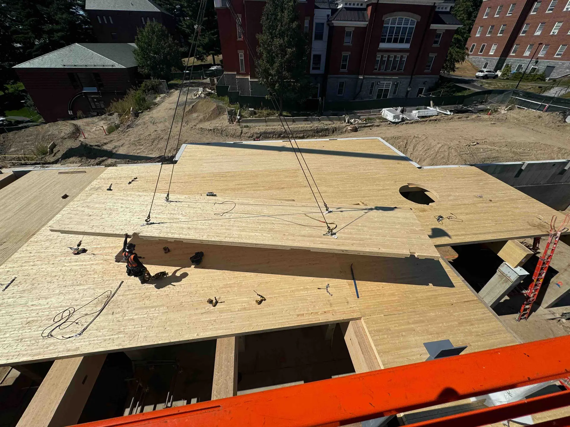 Cross timber flooring being placed by crane and handled by worker at Amherst College