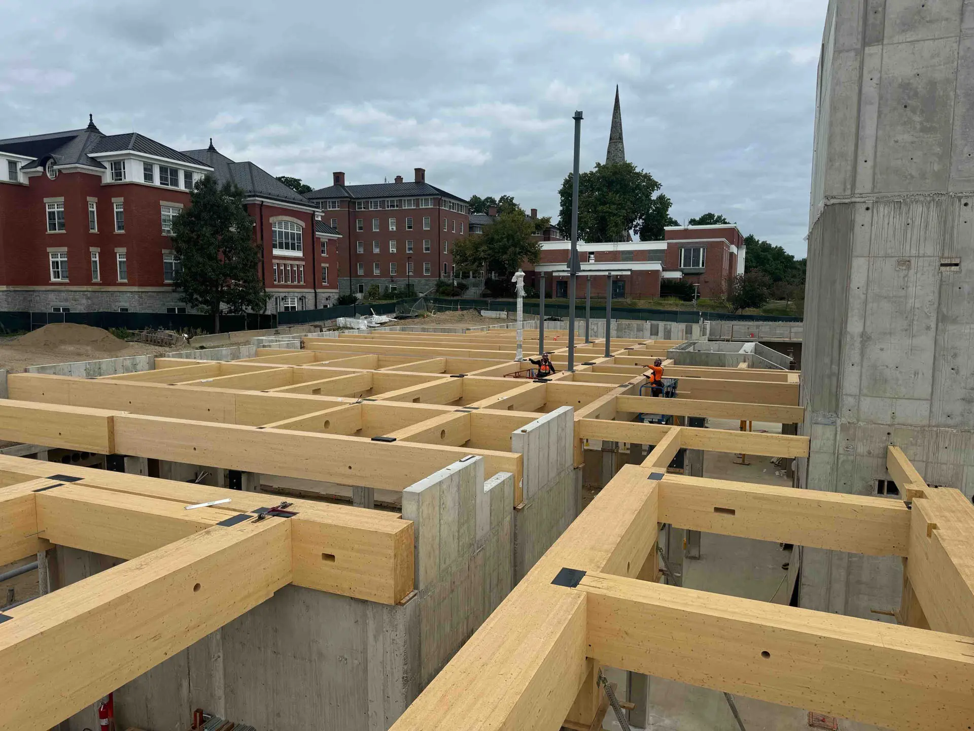 Two workers in cross timber struts between concrete foundation at amherst college