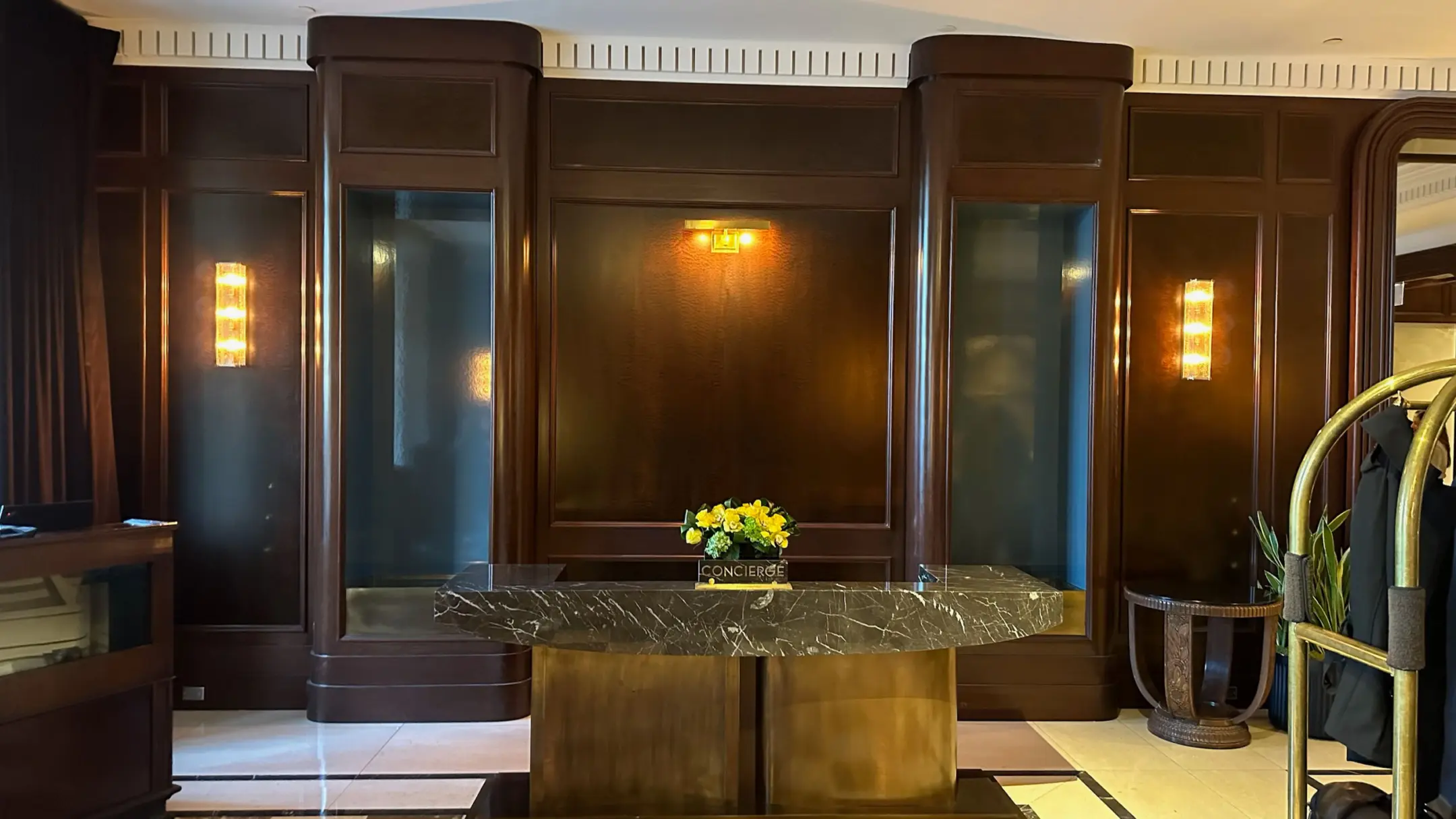 Concierge desk with bellhop cart and dark wood millwork behind