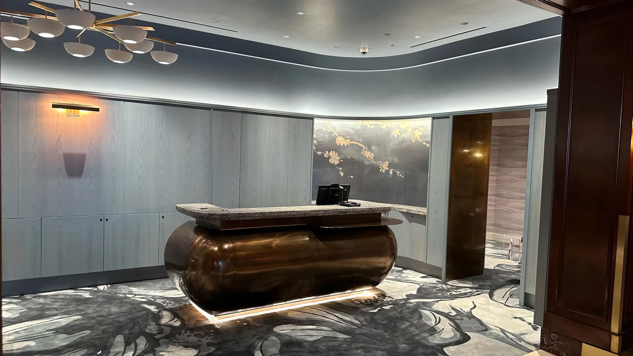 Concierge desk in steel blue room with low clearance chandelier