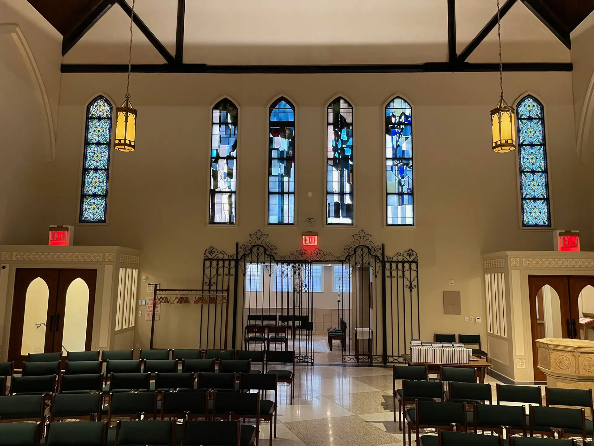Blue stained glass windows on back wall of church sanctuary