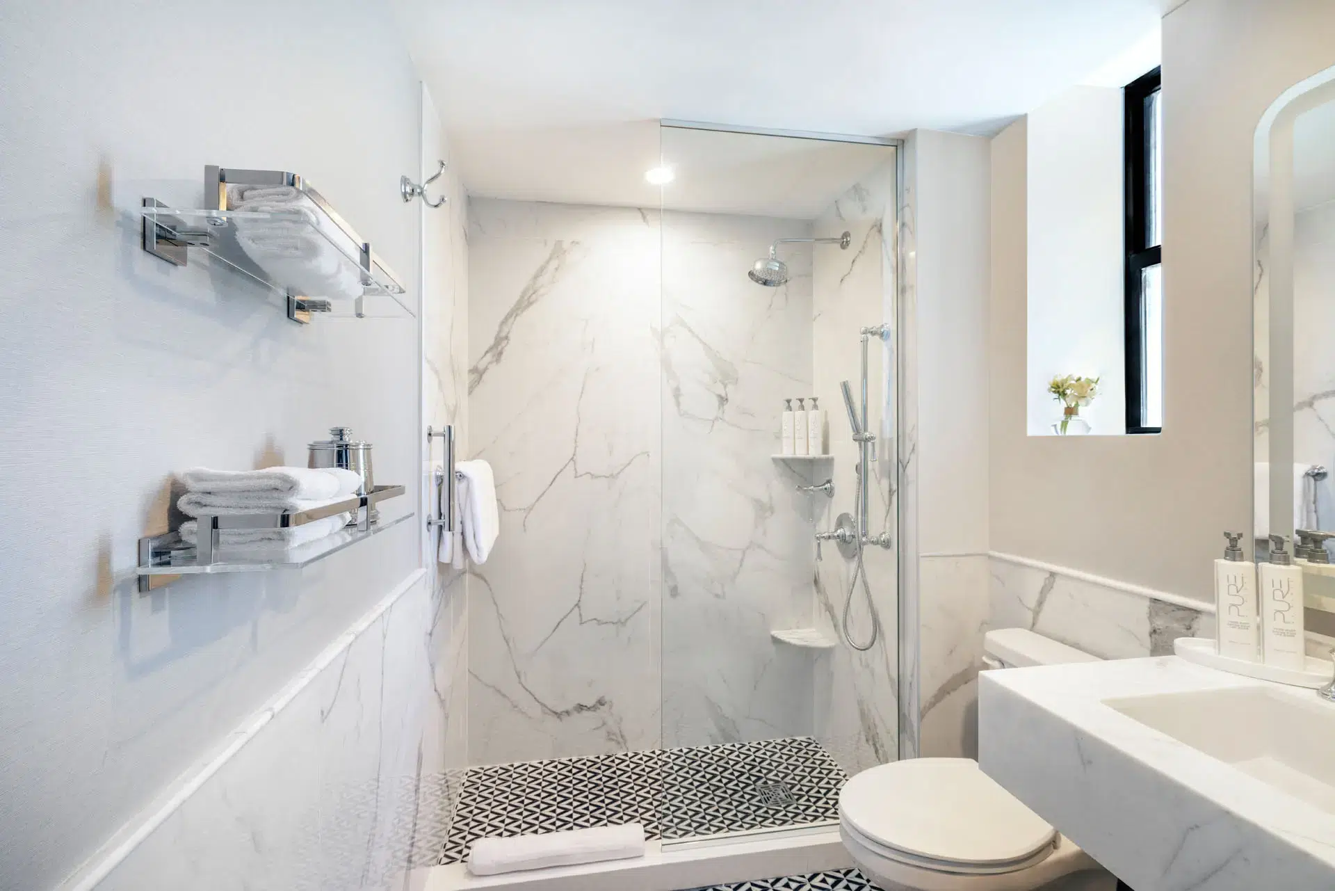 White marble bathroom with glass door shower and black trim window