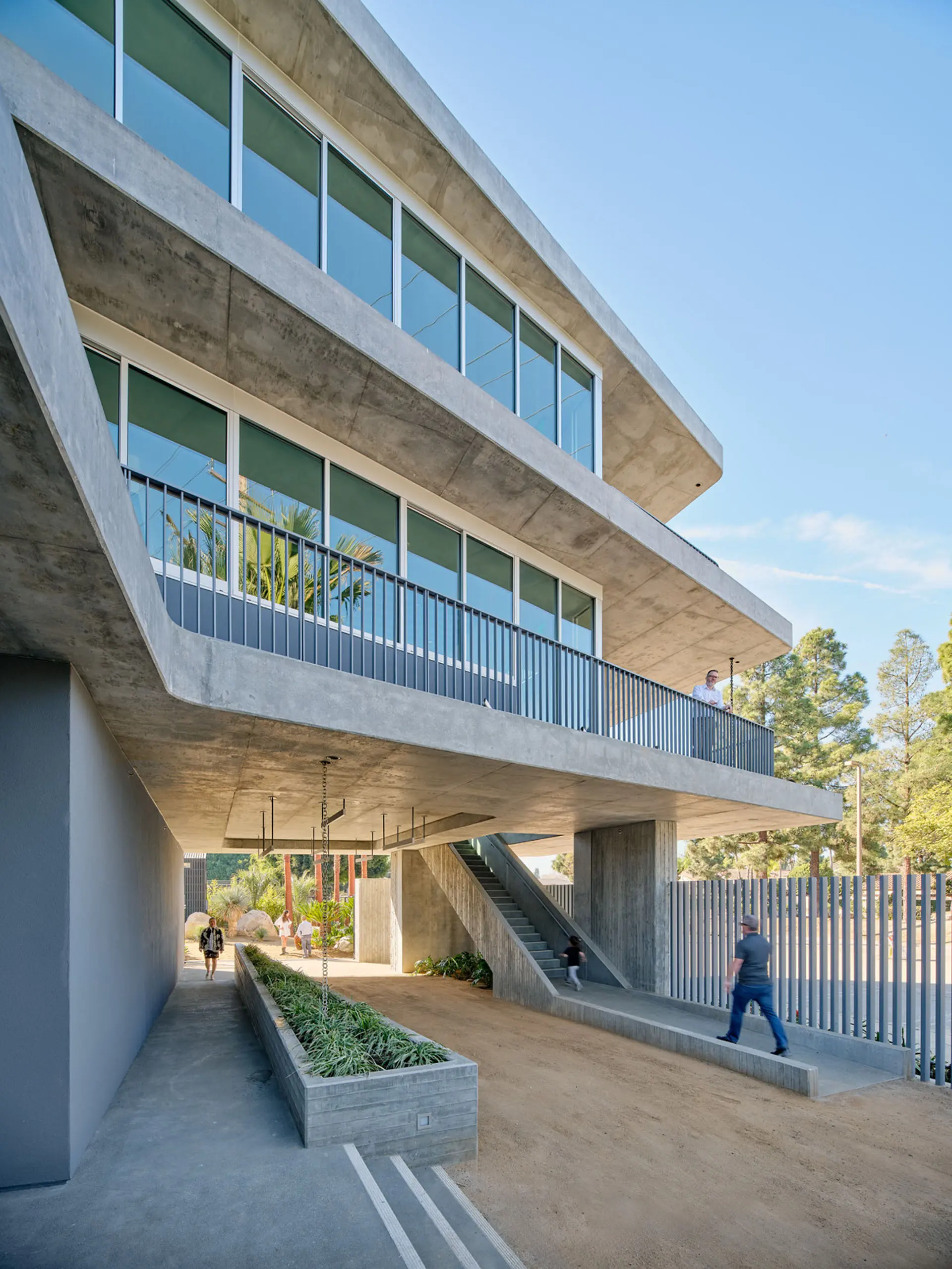 Three story concrete and glass building with man walking to stairs