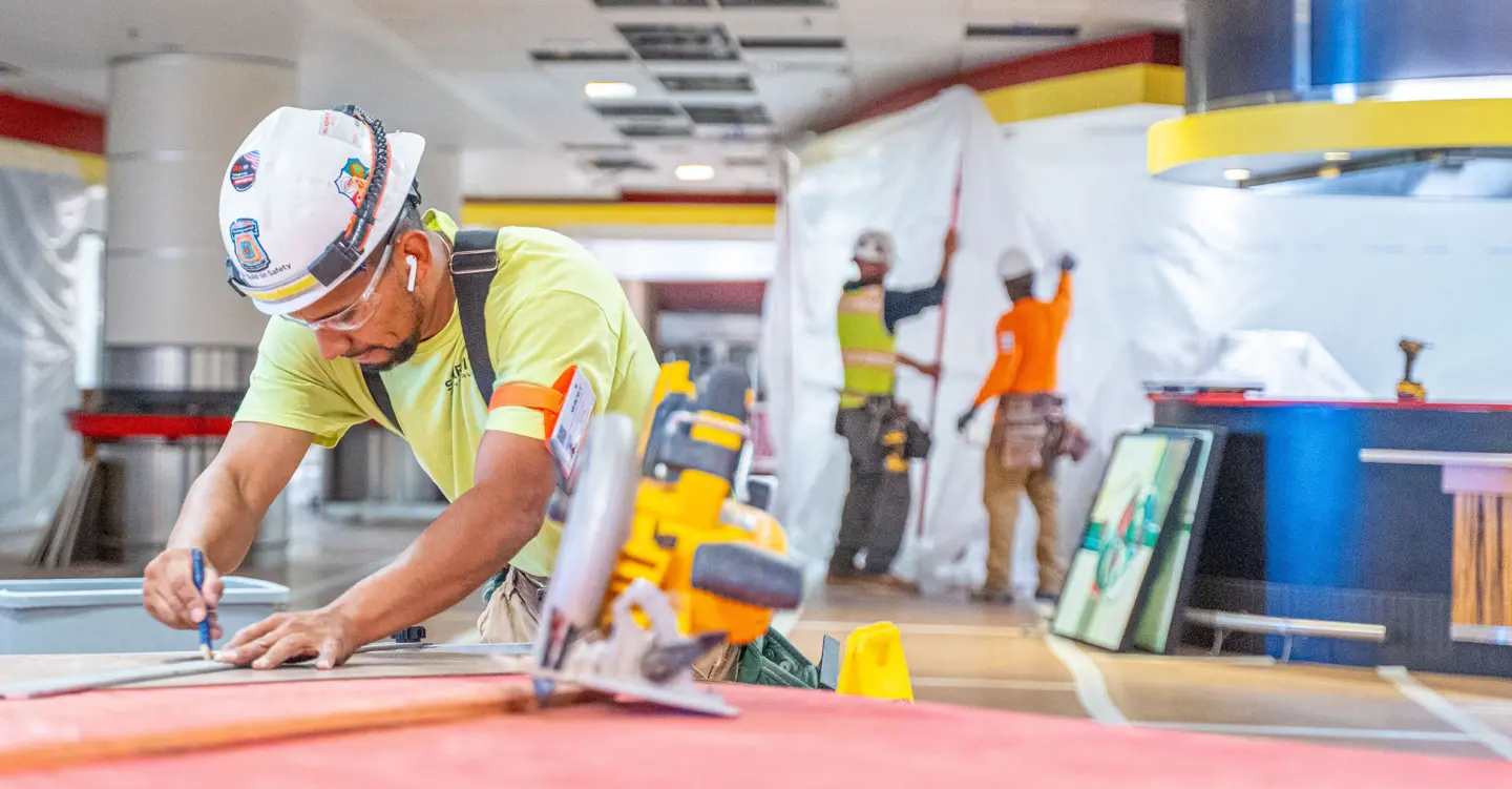 Workers hanging up plastic on the walls and drawing on construction materials