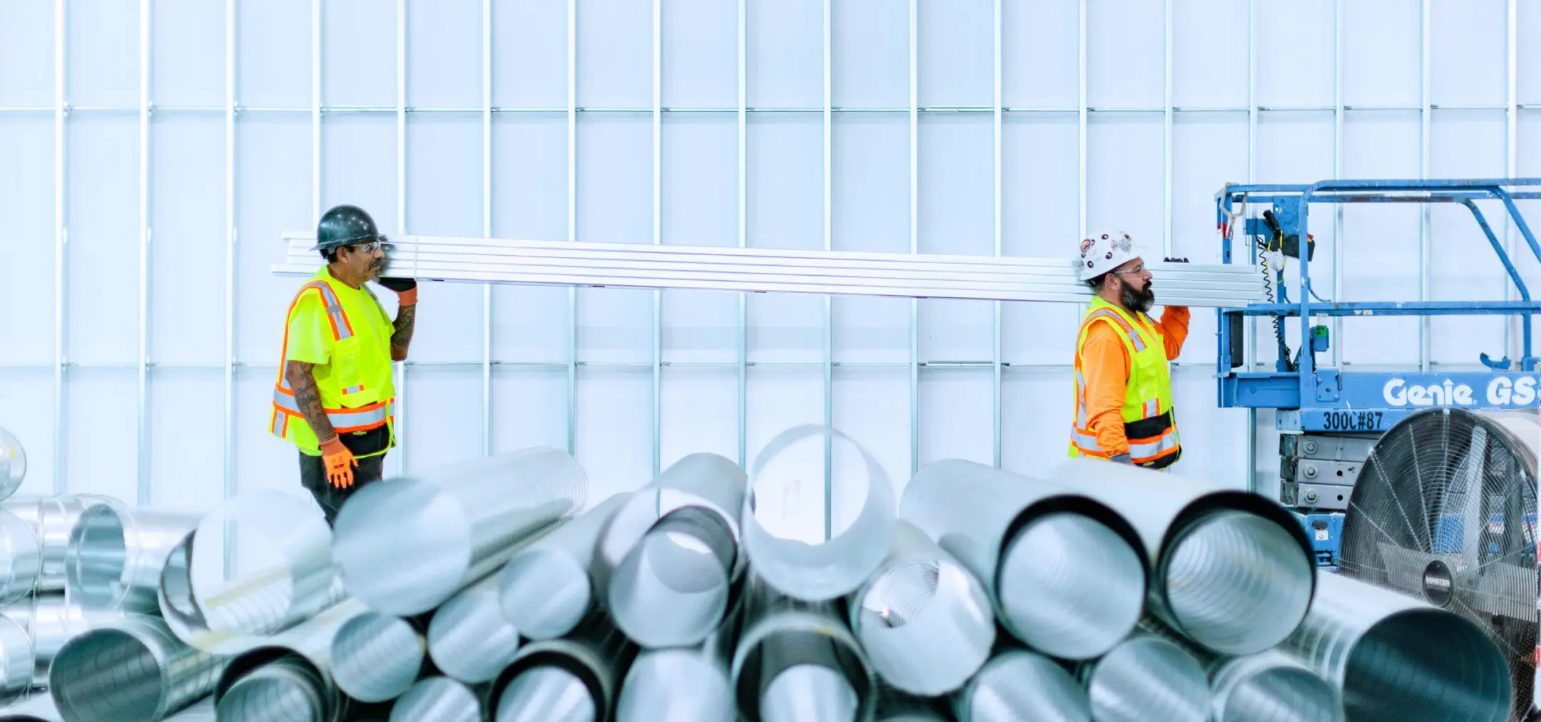Two men carrying metal bars