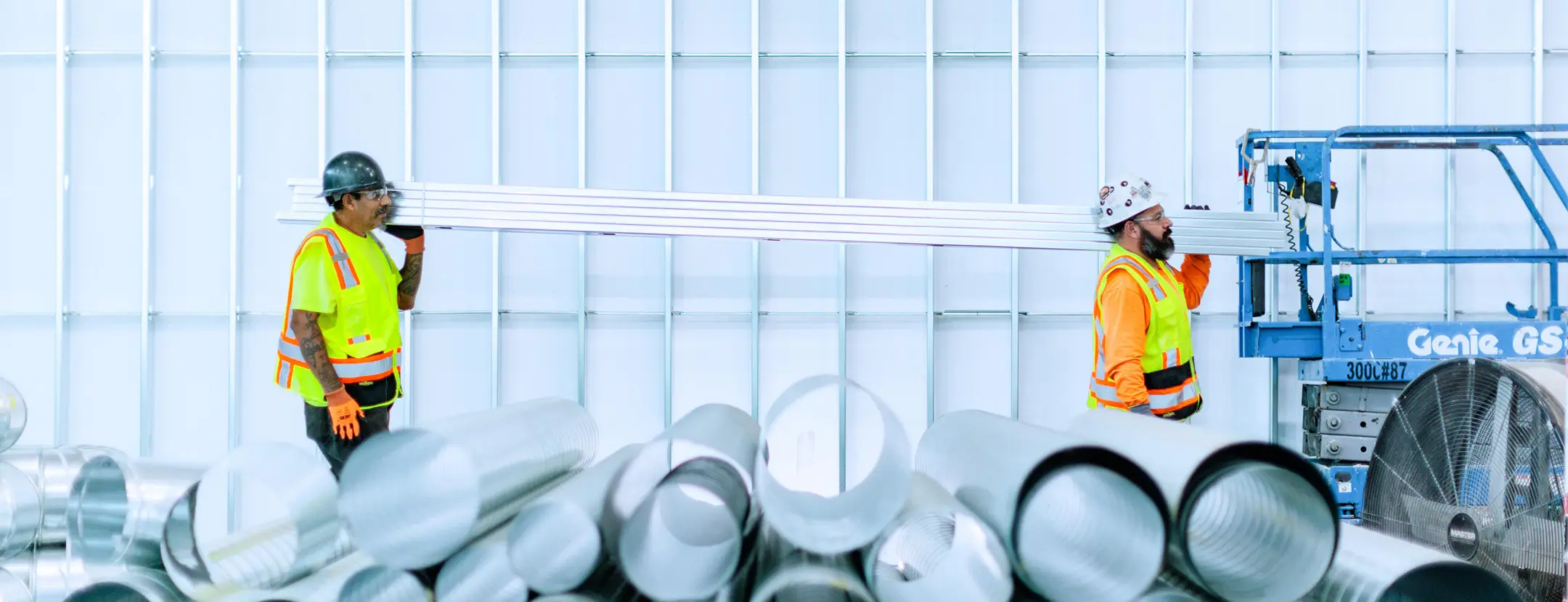 Two men carrying metal beams