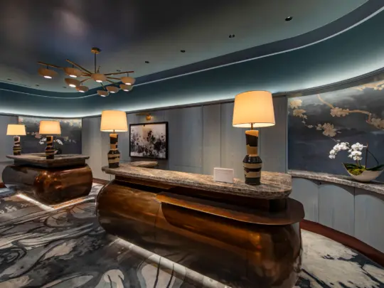 Two concierge desks with marble tops in rounded steel blue room with orchids behind