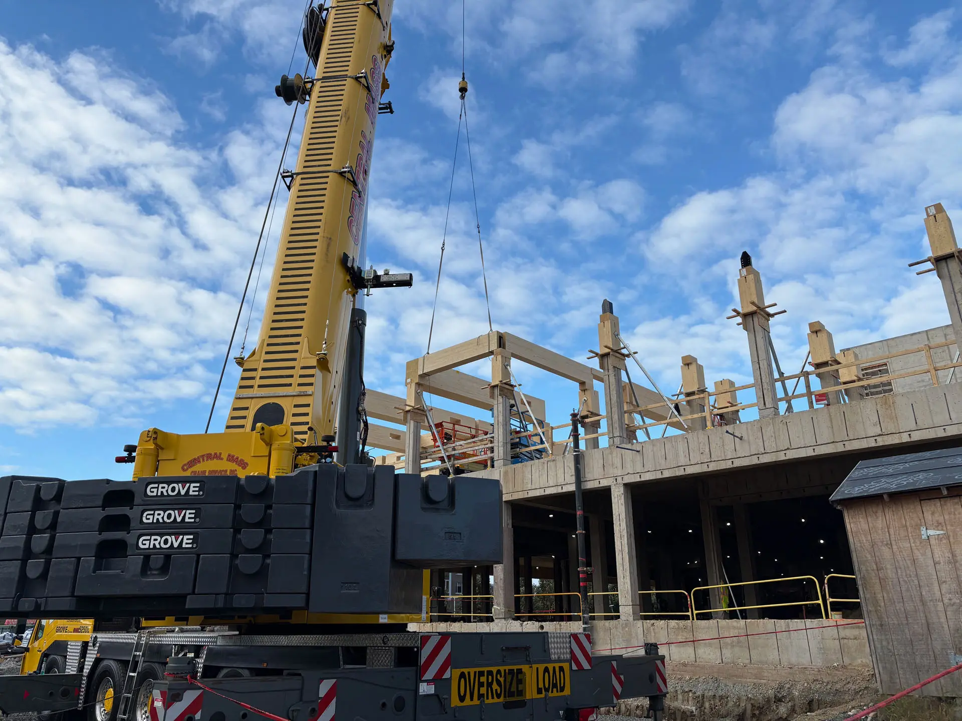 oversize yellow crane placing cross timber beam at Amherst College