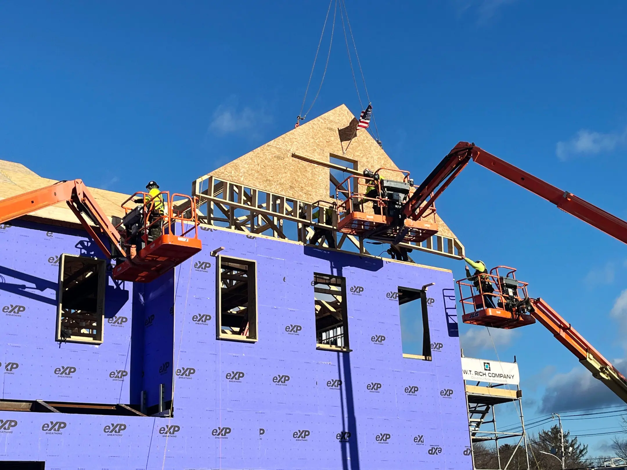 Roof truss with American flag being placed by three cherrypickers at Middleton Municipal Complex