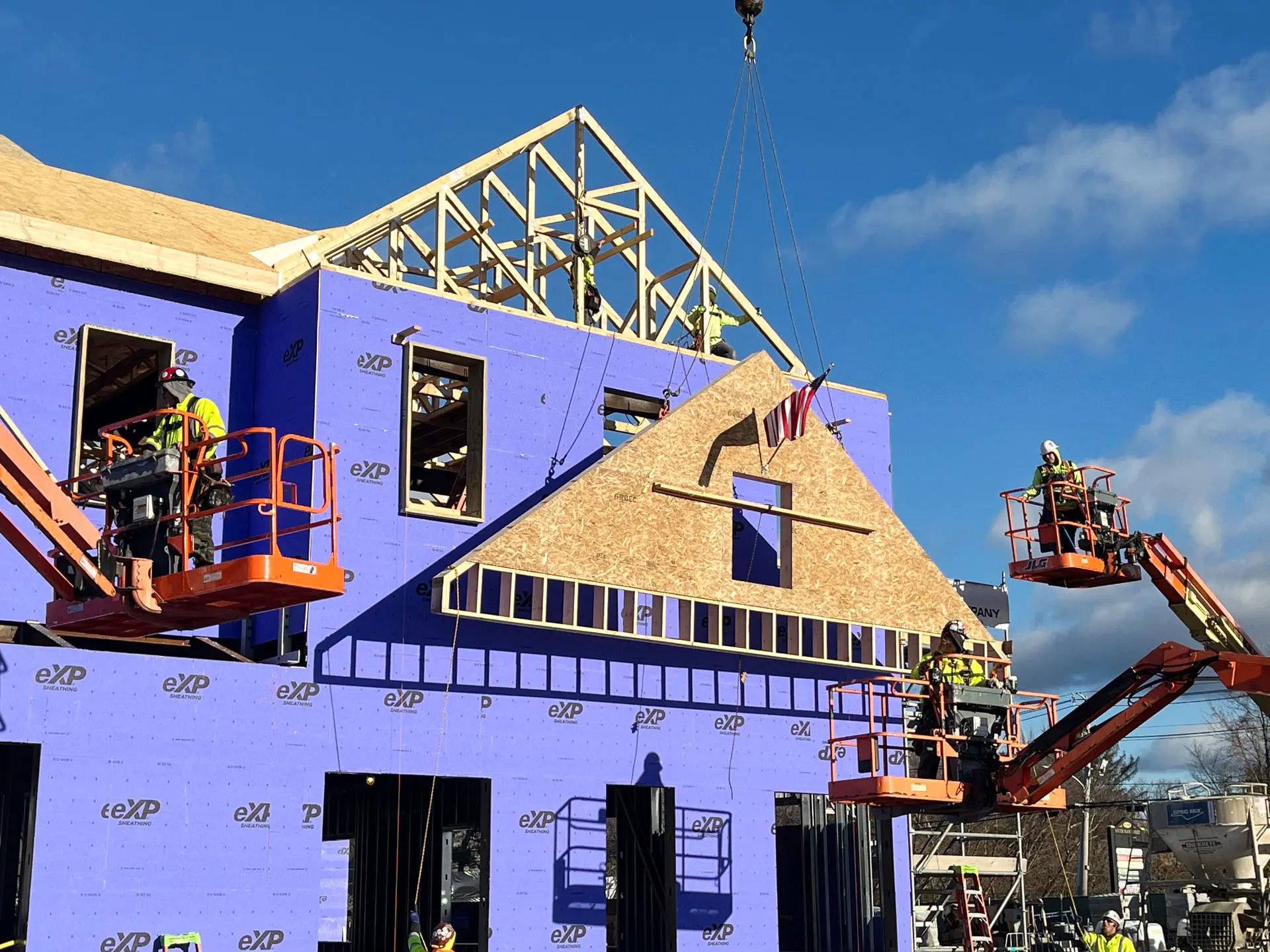 three cherry pickers with workers placing roof truss at Middleton Municipal Complex